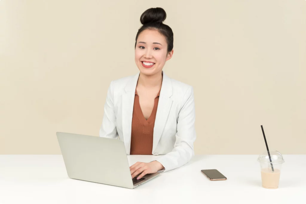 asian woman sitting at the desk smiling to the camera